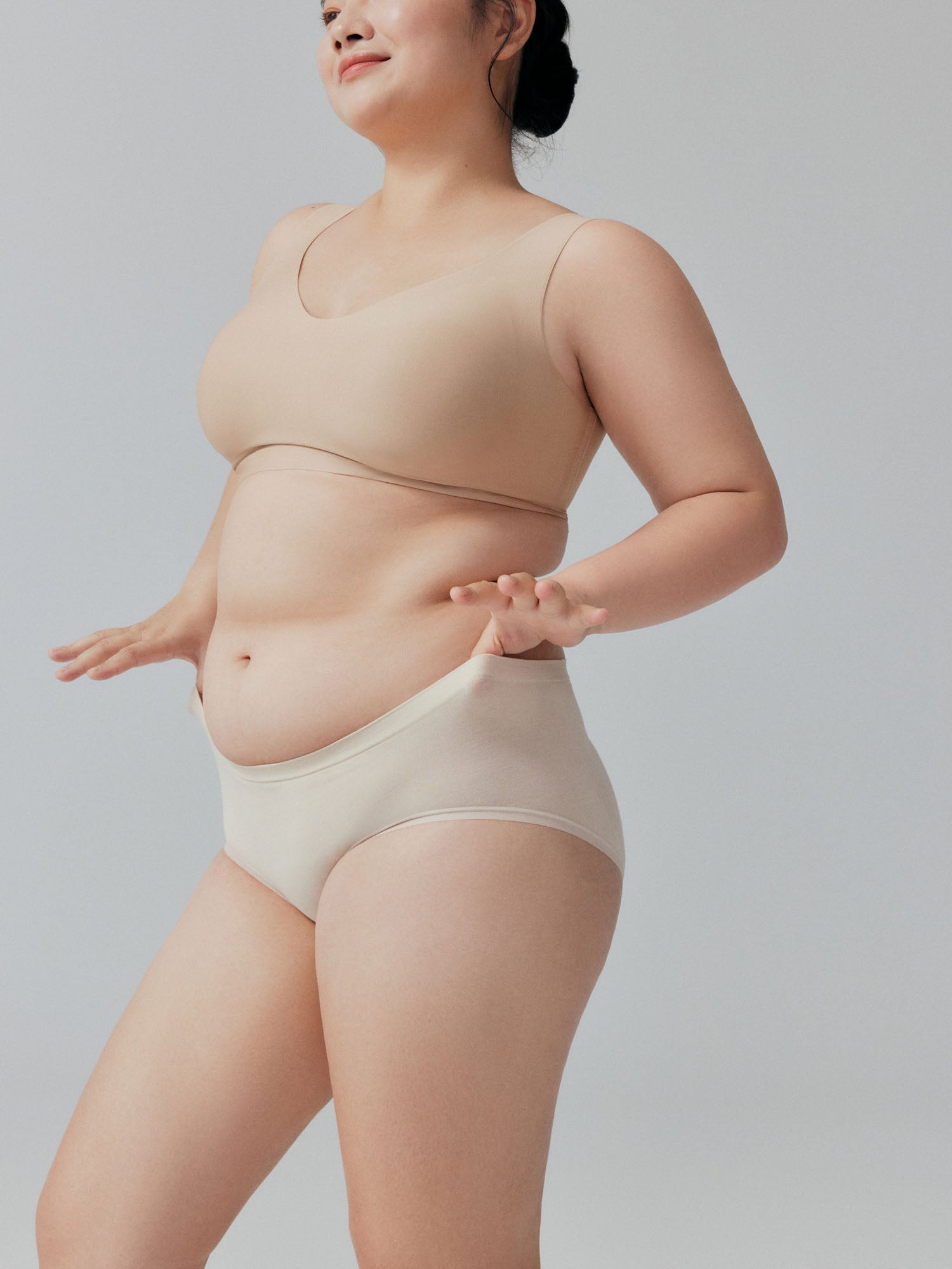 Model wearing beige bra and briefs on a plain background.
