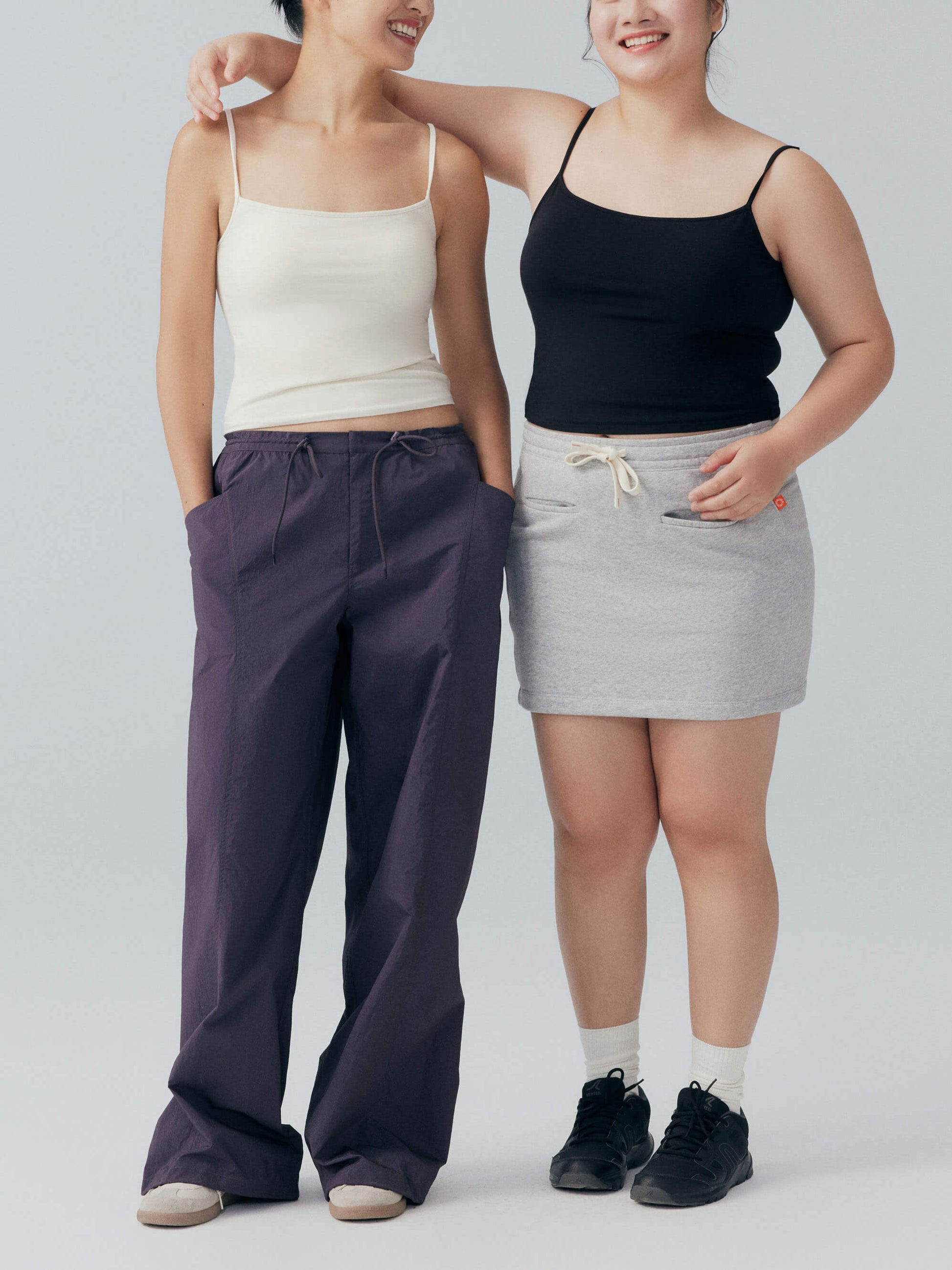 Two models smiling and wearing black and white camisoles 