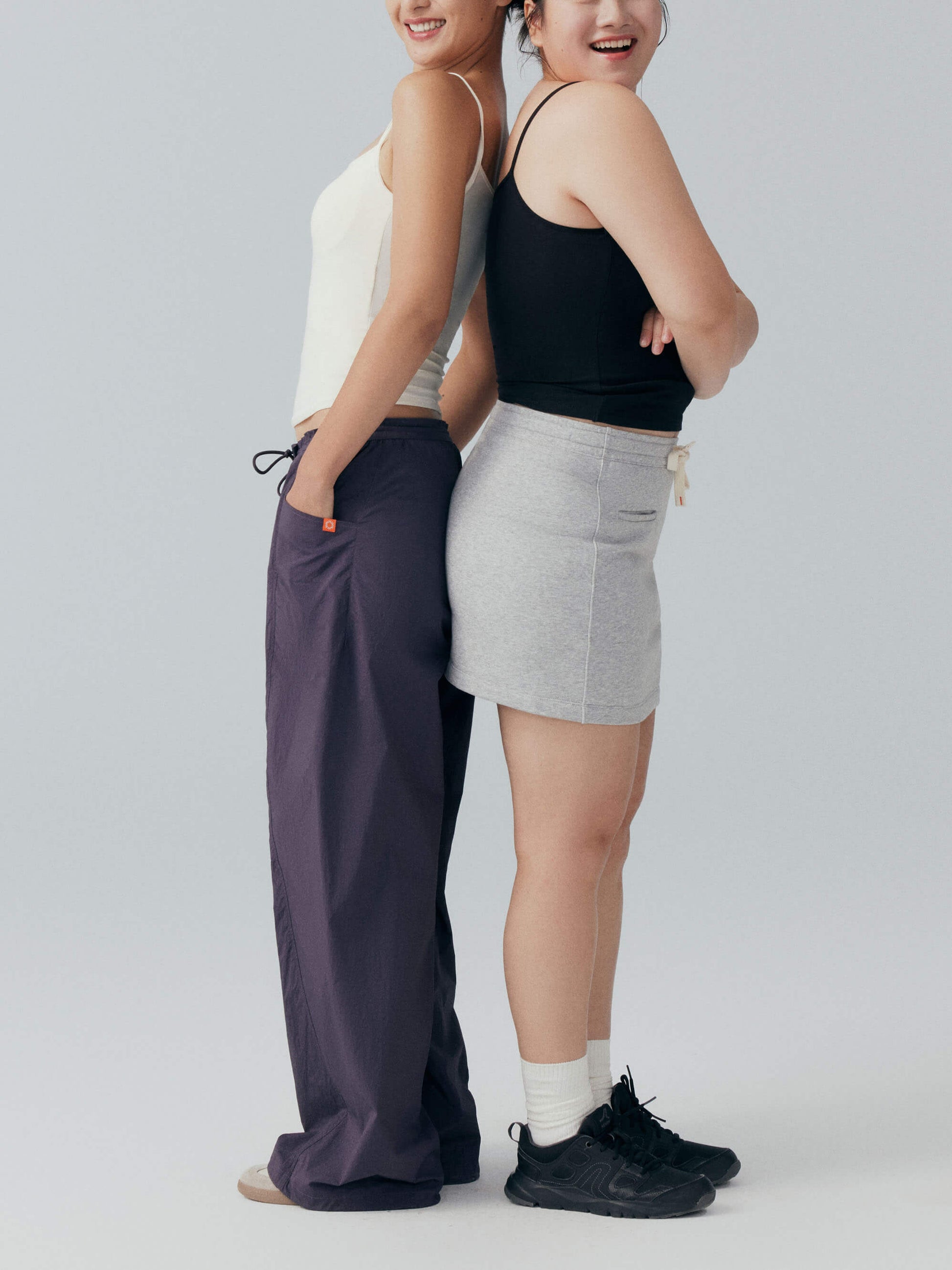 Two models smiling and wearing black and white camisoles 