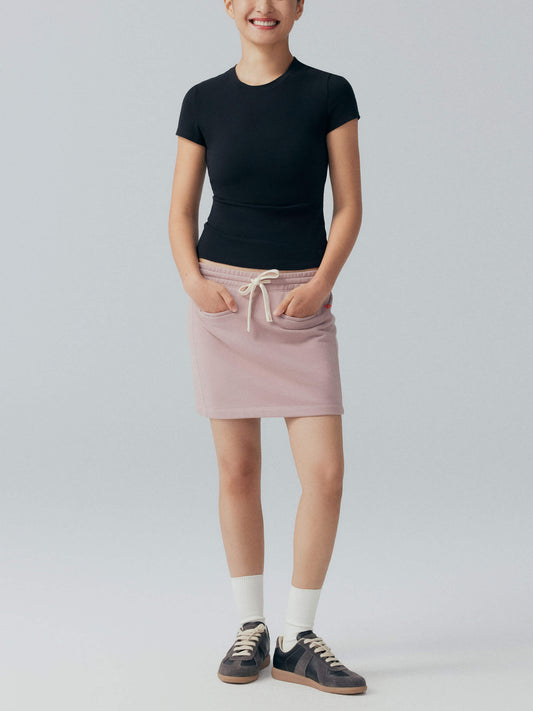 Model wearing black tee with pink skirt.