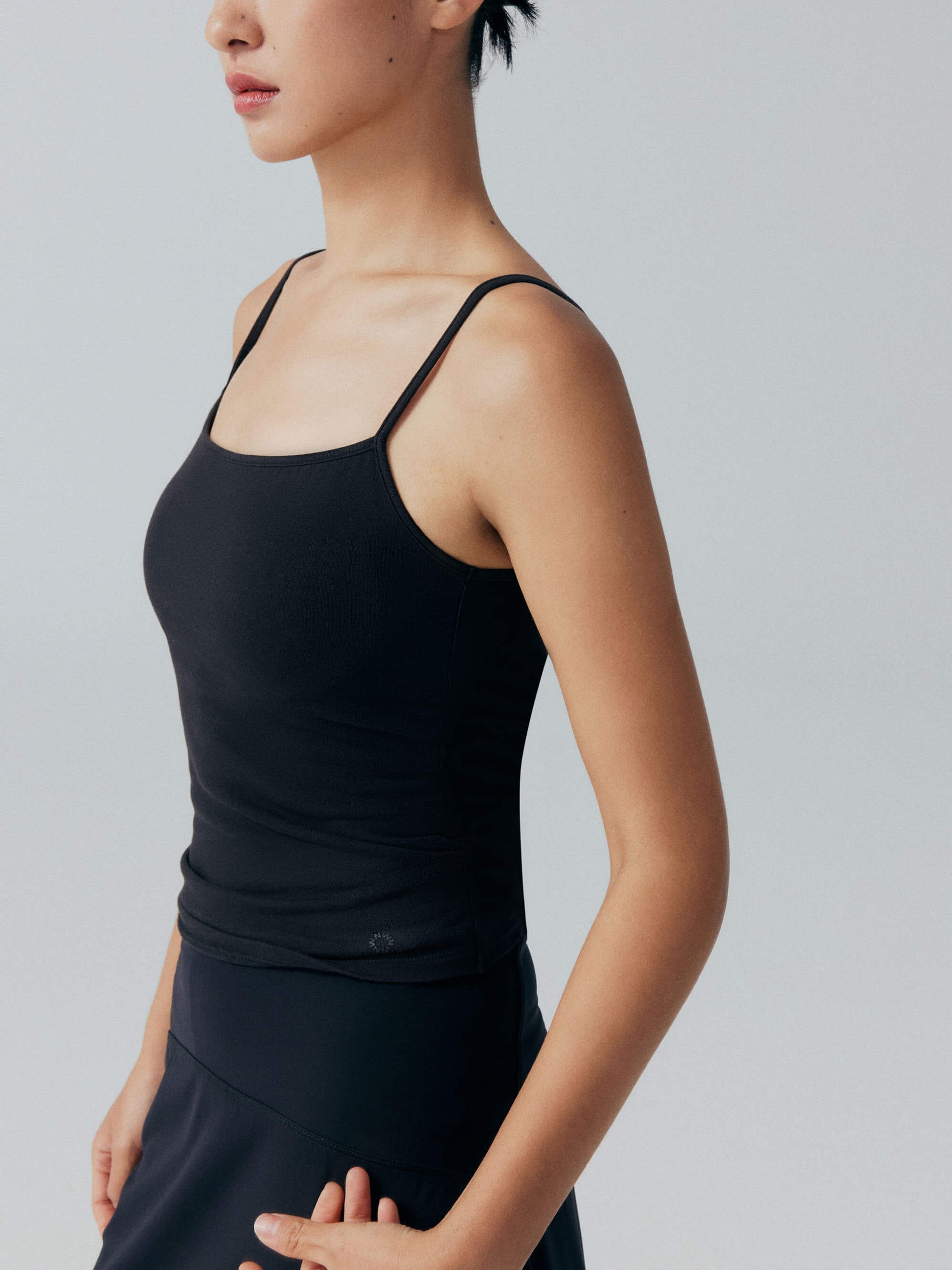 Side view of model wearing black camisole top.