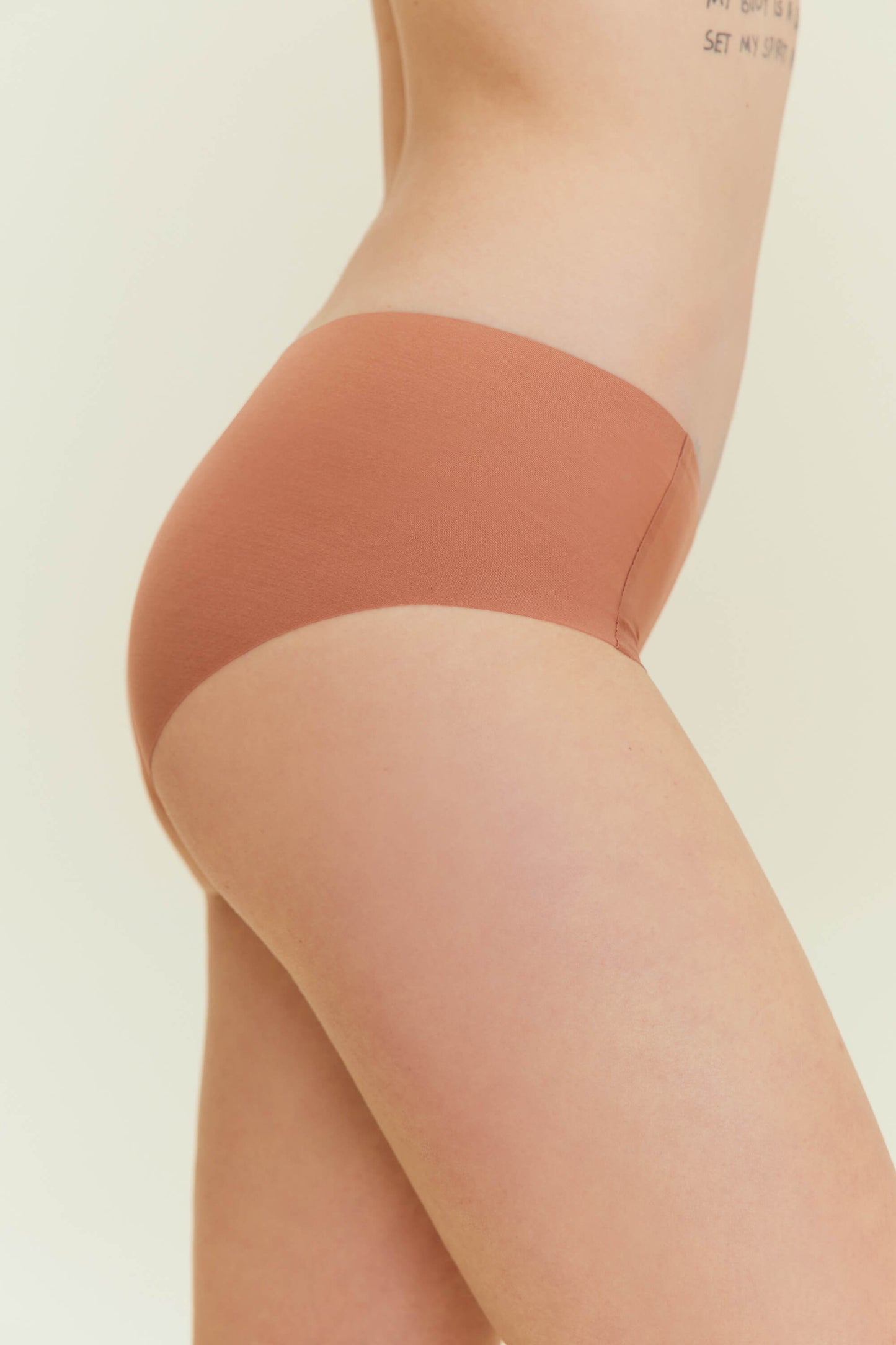 Side view of woman wearing rust-colored underwear