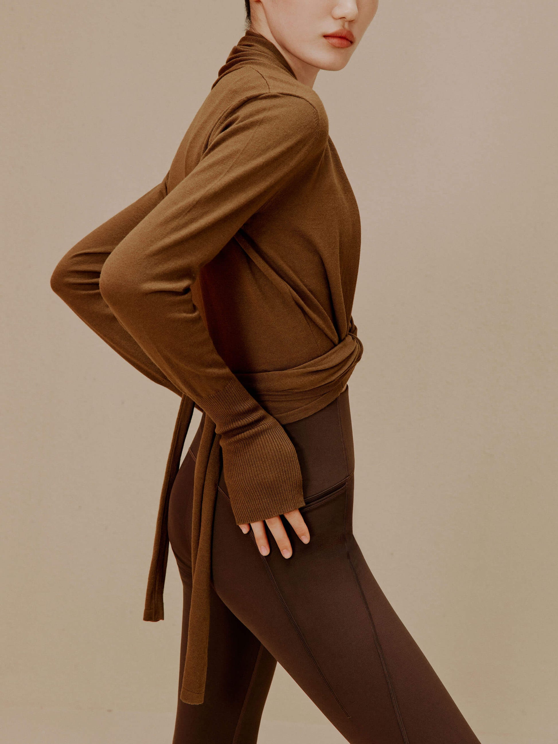 side of woman in brown wrap up cardigan