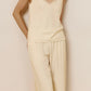 Front view of model wearing silk blend cream-colored V-neck tank top with matching pajama pants.