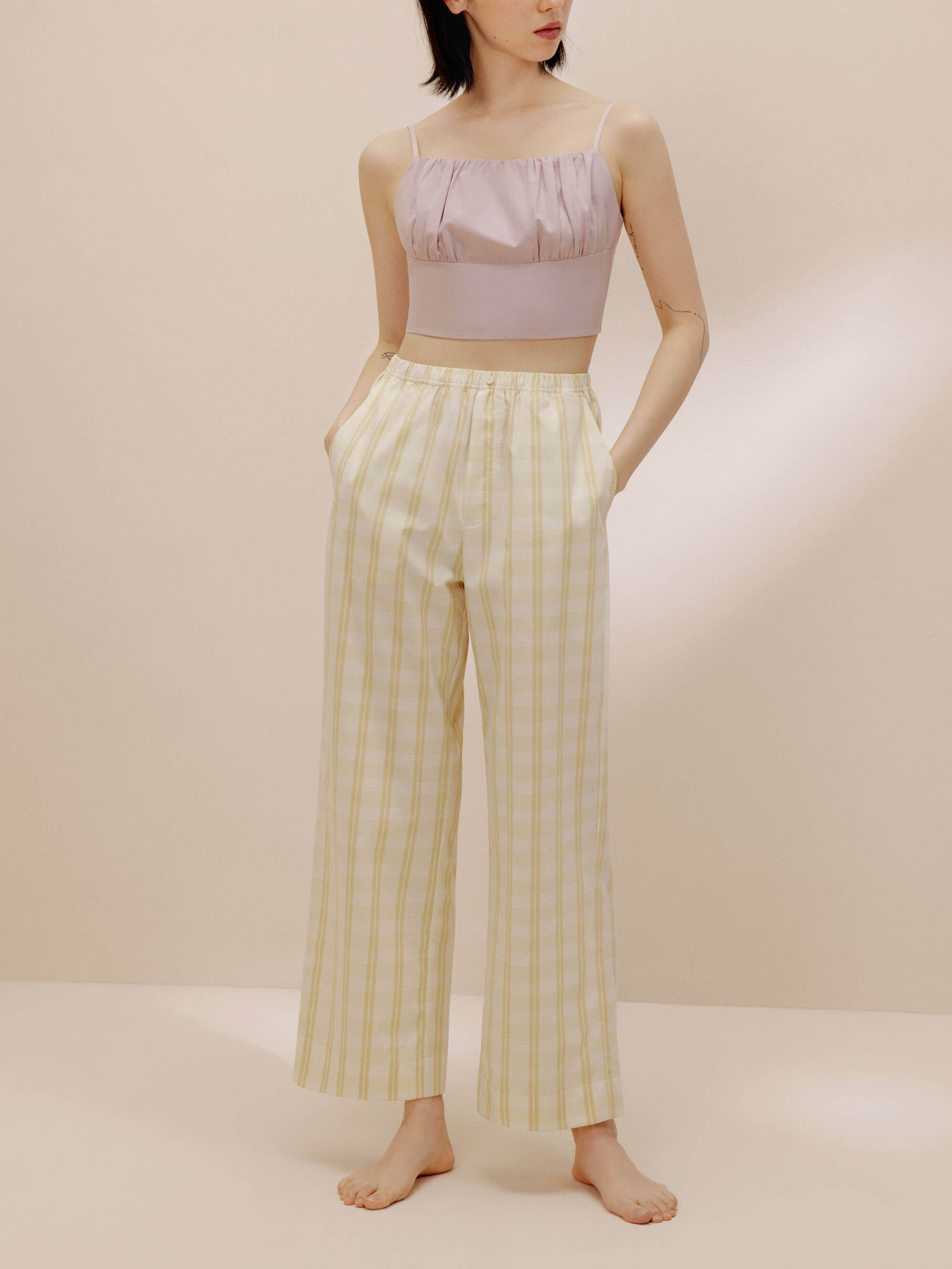 Woman wearing pink tank top and white and orange striped pajama pants