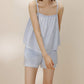 Woman wearing light blue pajama tank top and matching shorts