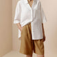 Woman wearing white short sleeve button down shirt and tan Bermuda shorts