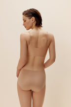 Model wearing a beige bodysuit against a beige background