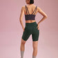 back of a woman wearing a black sports bra and green biker shorts. pair with grey socks and green shoes.