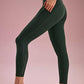 side of a woman wearing a green leggings, she put her hands in the side pockets. 