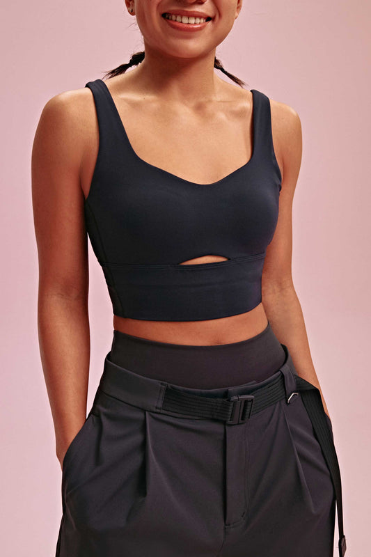a woman wearing a long black sports bra and black pants