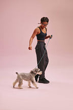 a woman wearing a black long sports bra and black pants with a dog
