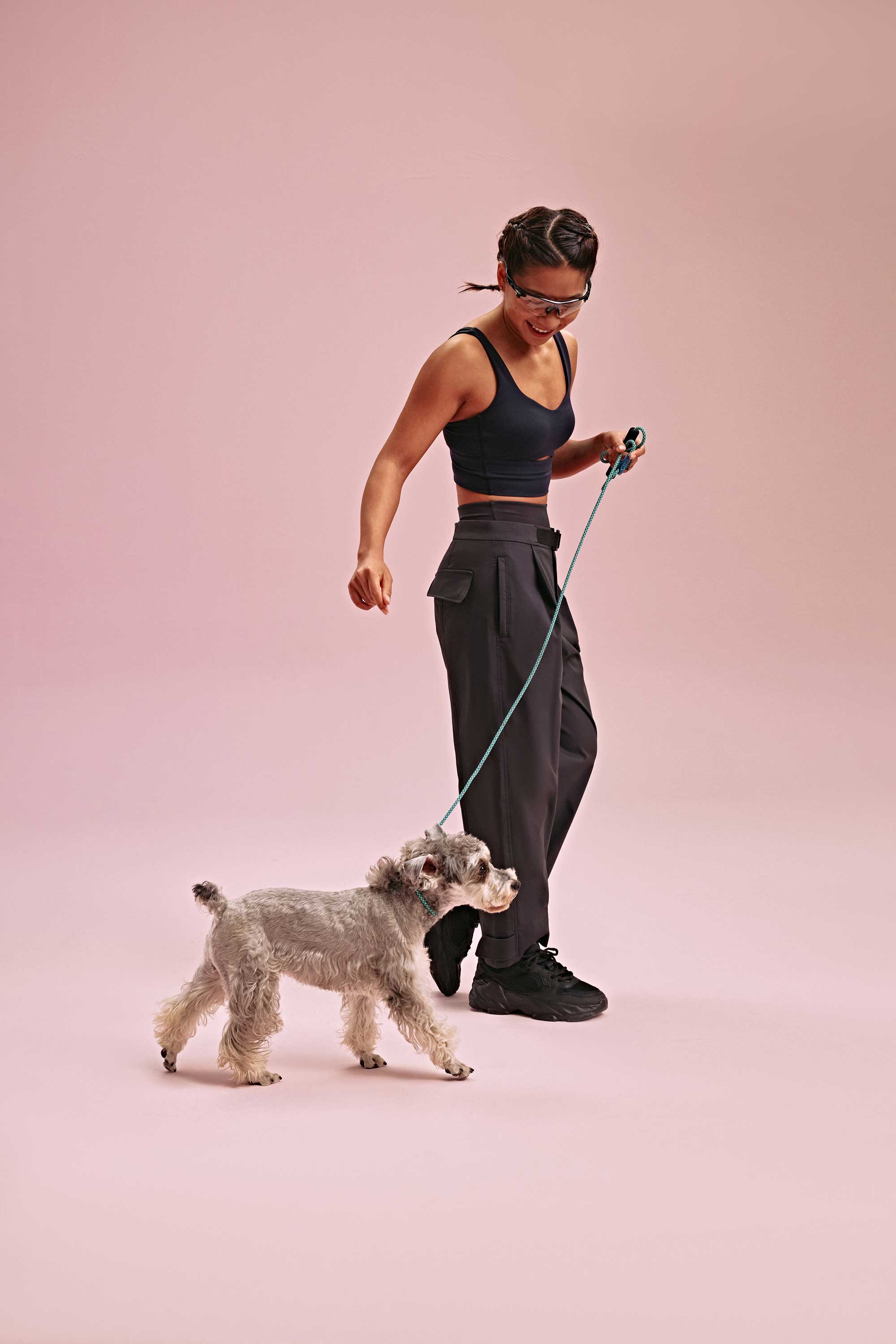 a woman wearing a black long sports bra and black pants with a dog