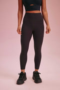 a woman wearing a black sports bra and black leggings and black sneakers.