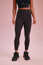 a woman wearing a black sports bra and black leggings and black sneakers.