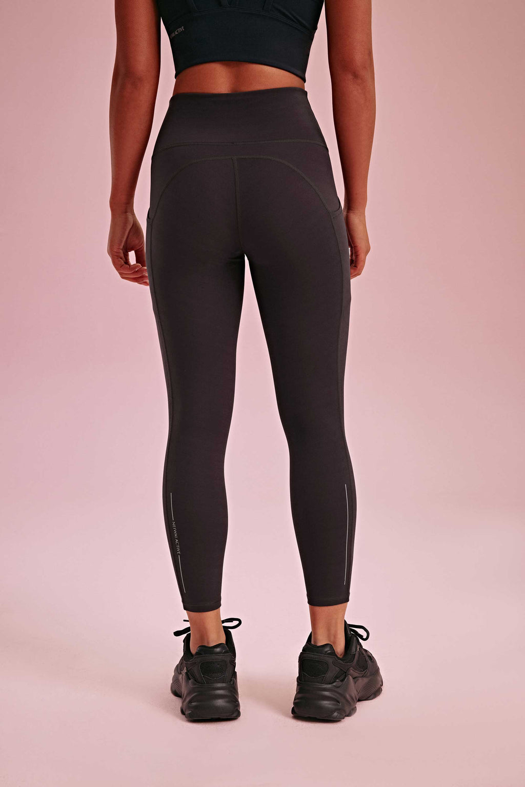 back of a woman wearing a black sports bra and black leggings.