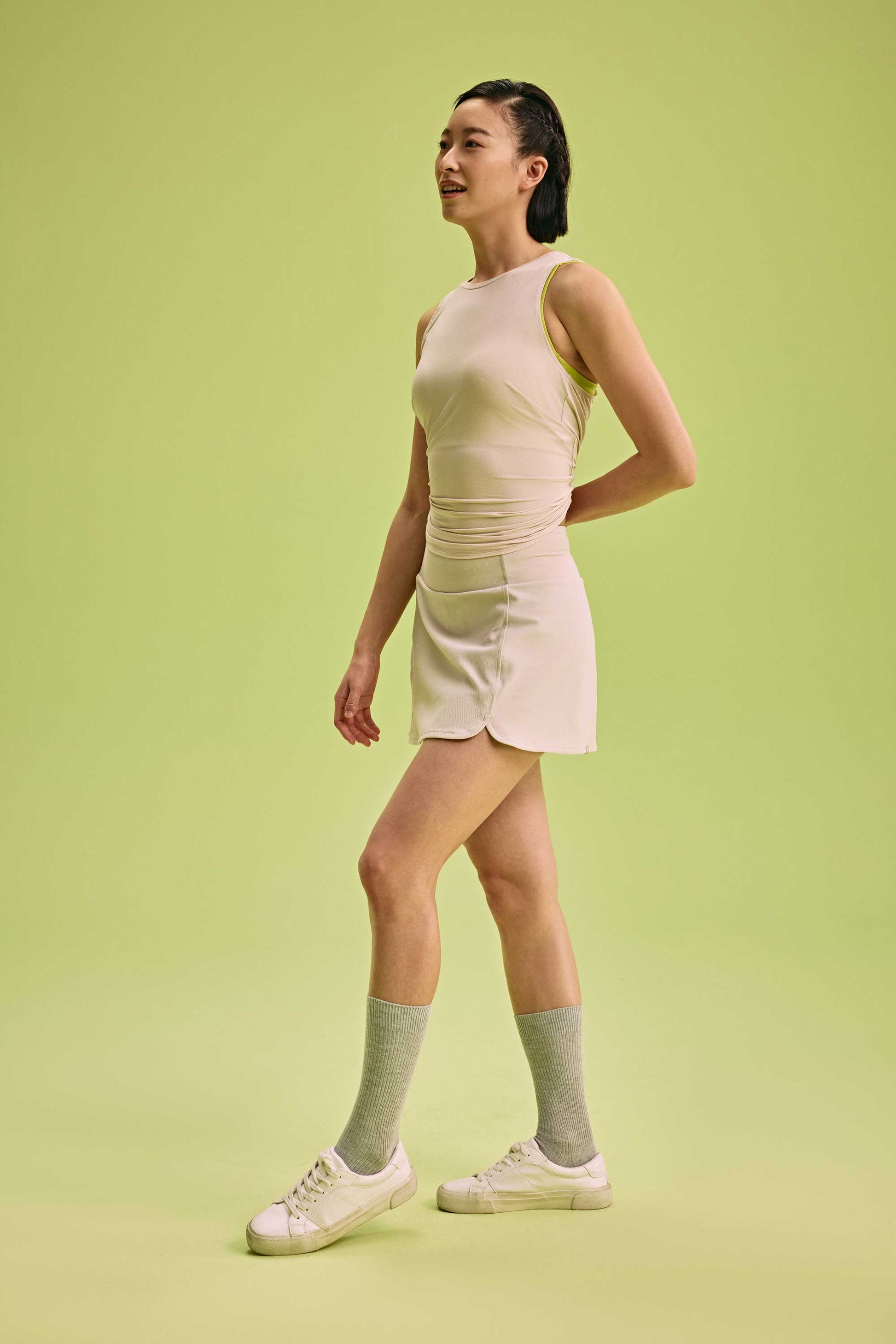a woman wearing a cream tank and skirt