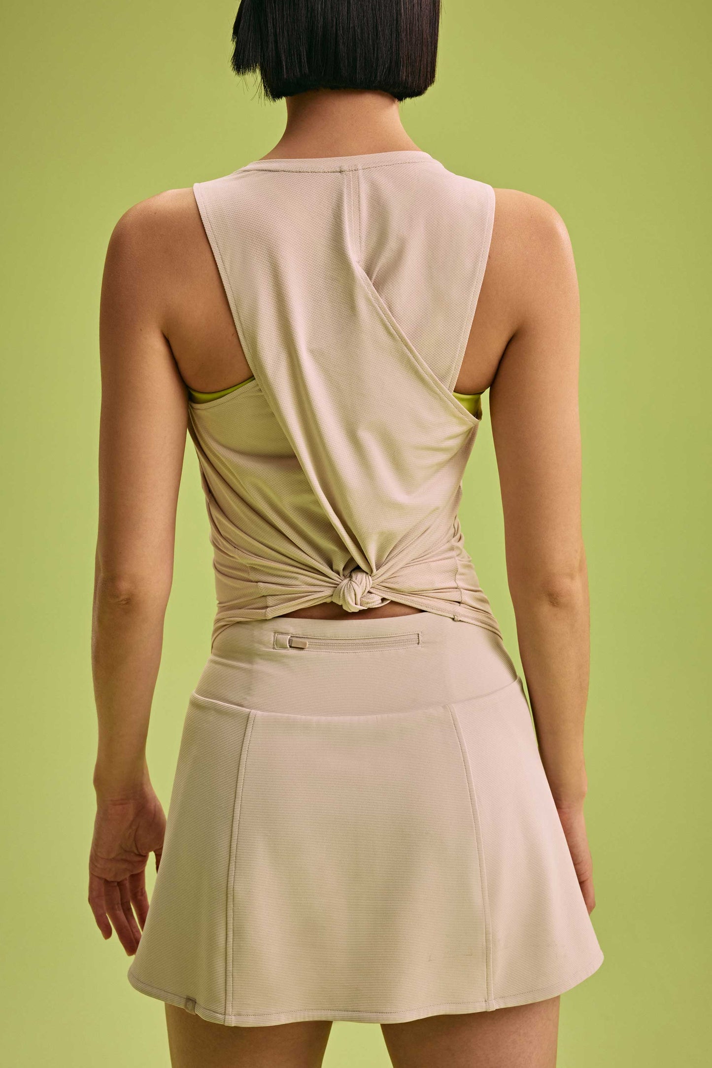 back of a woman wearing cross back tank and cream skirt 