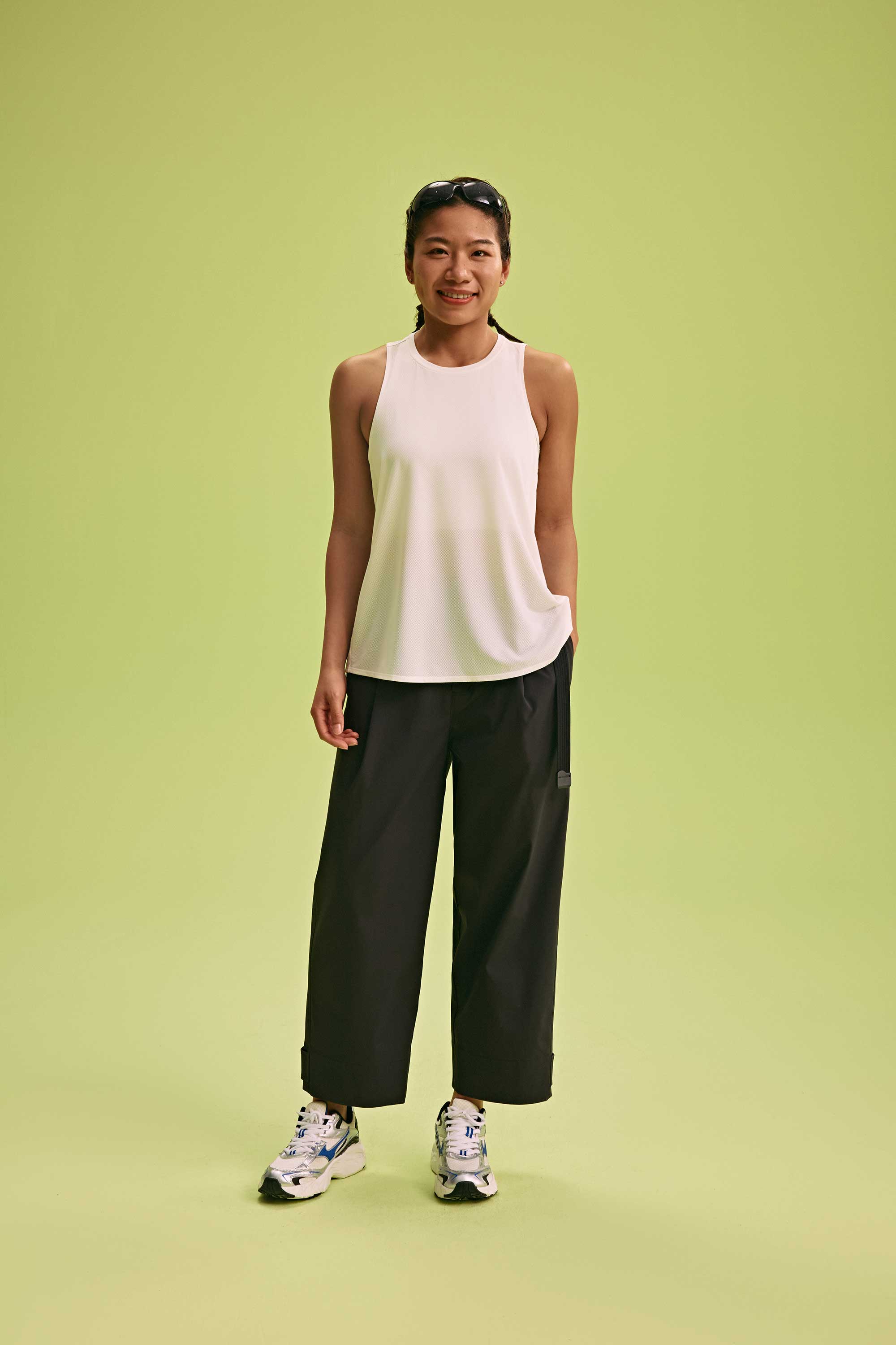 a woman wearing a white tank and black pants