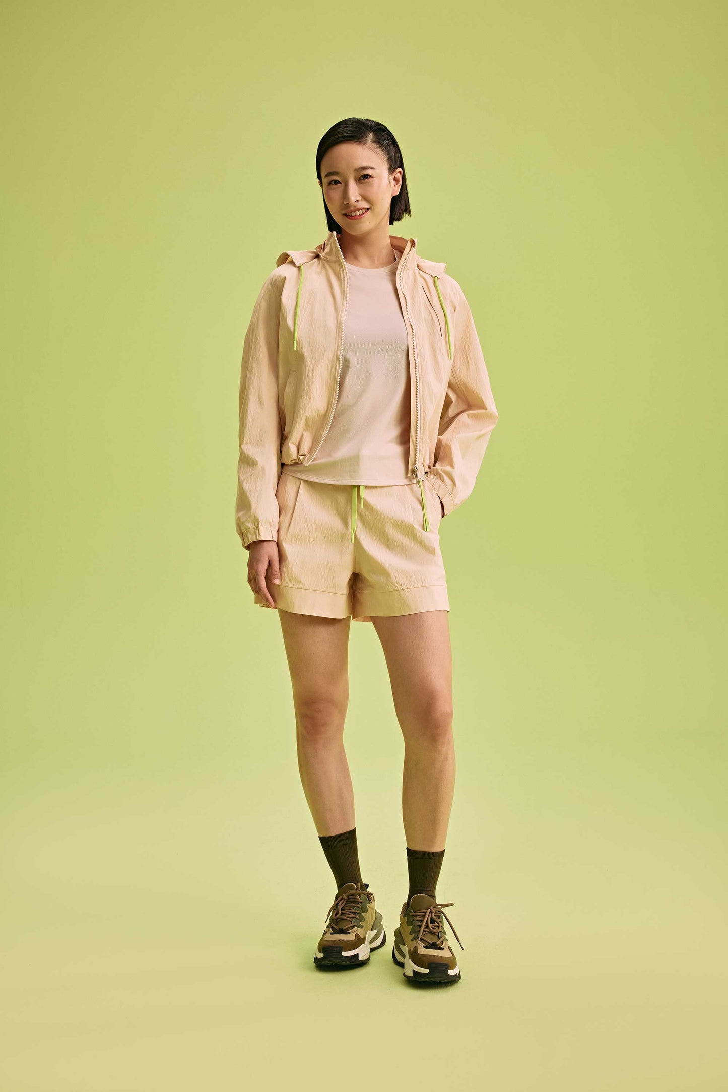 a woman wearing a light yellow jacket and shorts with t-shirt underneath