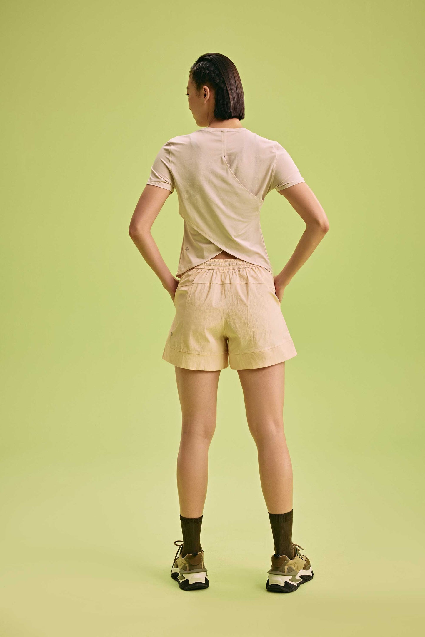 back of a woman wearing Cross-back T-Shirt and cream shorts