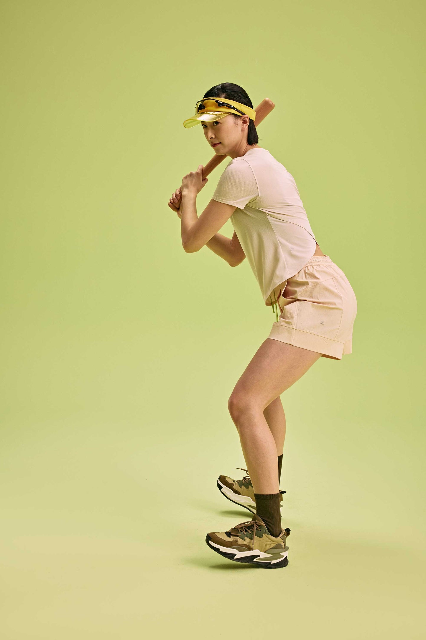 a woman holding baseball bat wearing cream top and shorts 