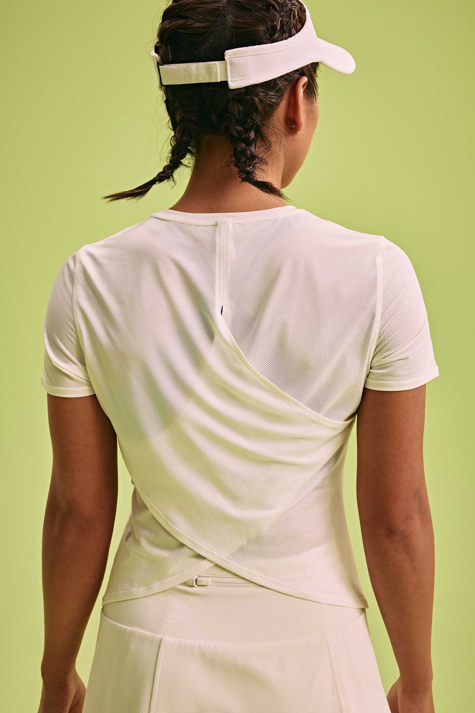 back of a woman wearing white Cross-back T-Shirt and a hat 