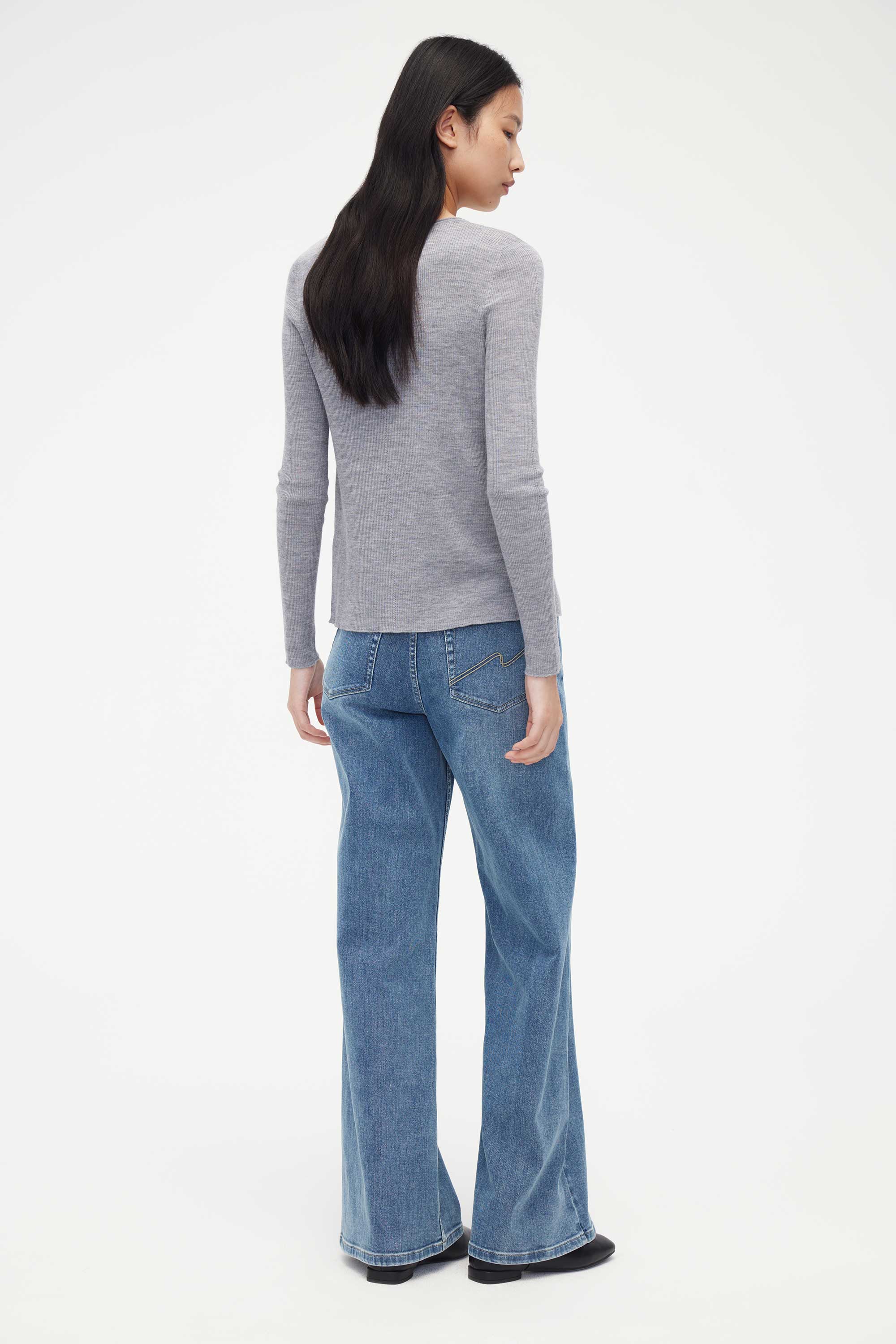 back of woman in grey cardigan and blue jeans