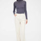 woman in purple mock neck sweater and white pants