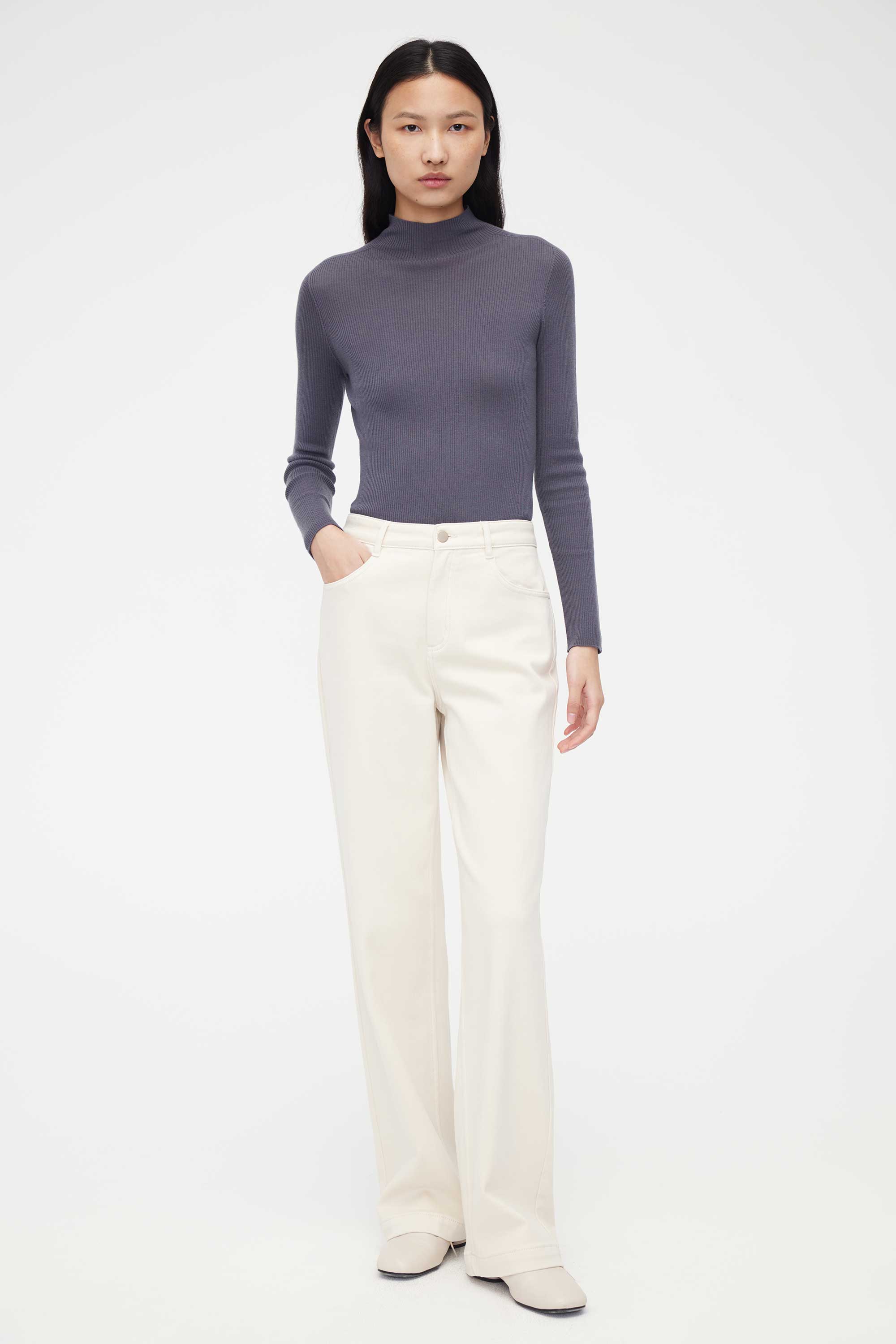 woman in purple mock neck sweater and white pants