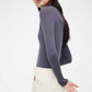 side look of woman in purple mock neck sweater and white pants