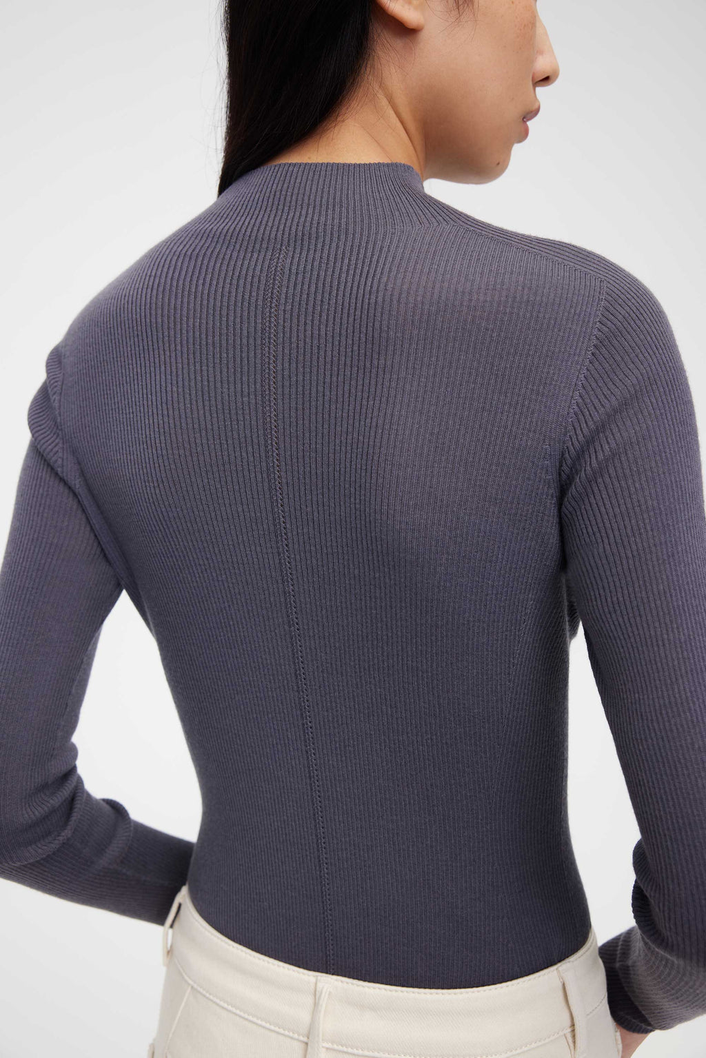 back of woman in purple mock neck sweater