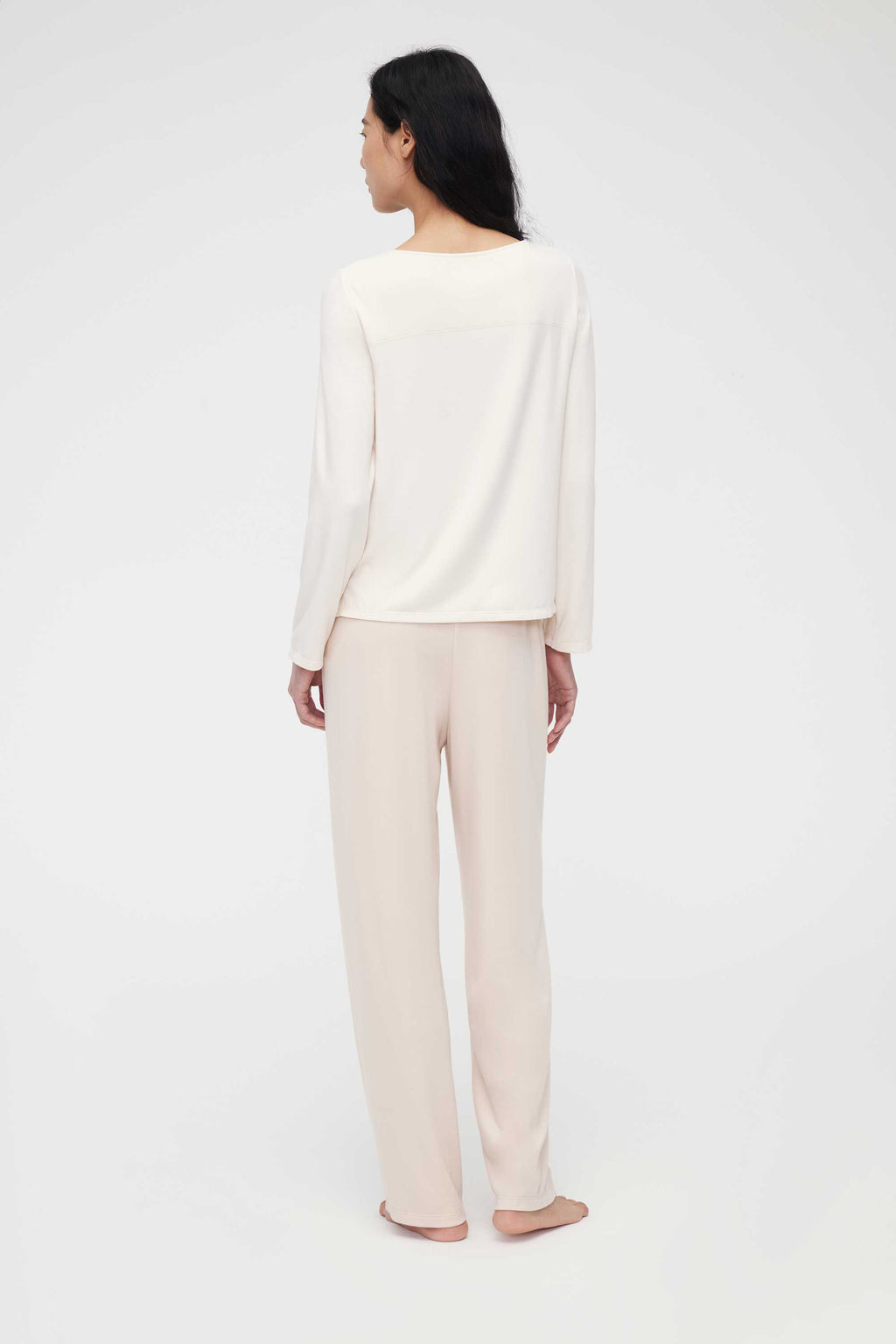 back of woman in cream pajama t-shirt and pajama pants