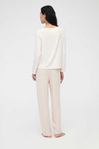 back of woman in cream pajama t-shirt and pajama pants