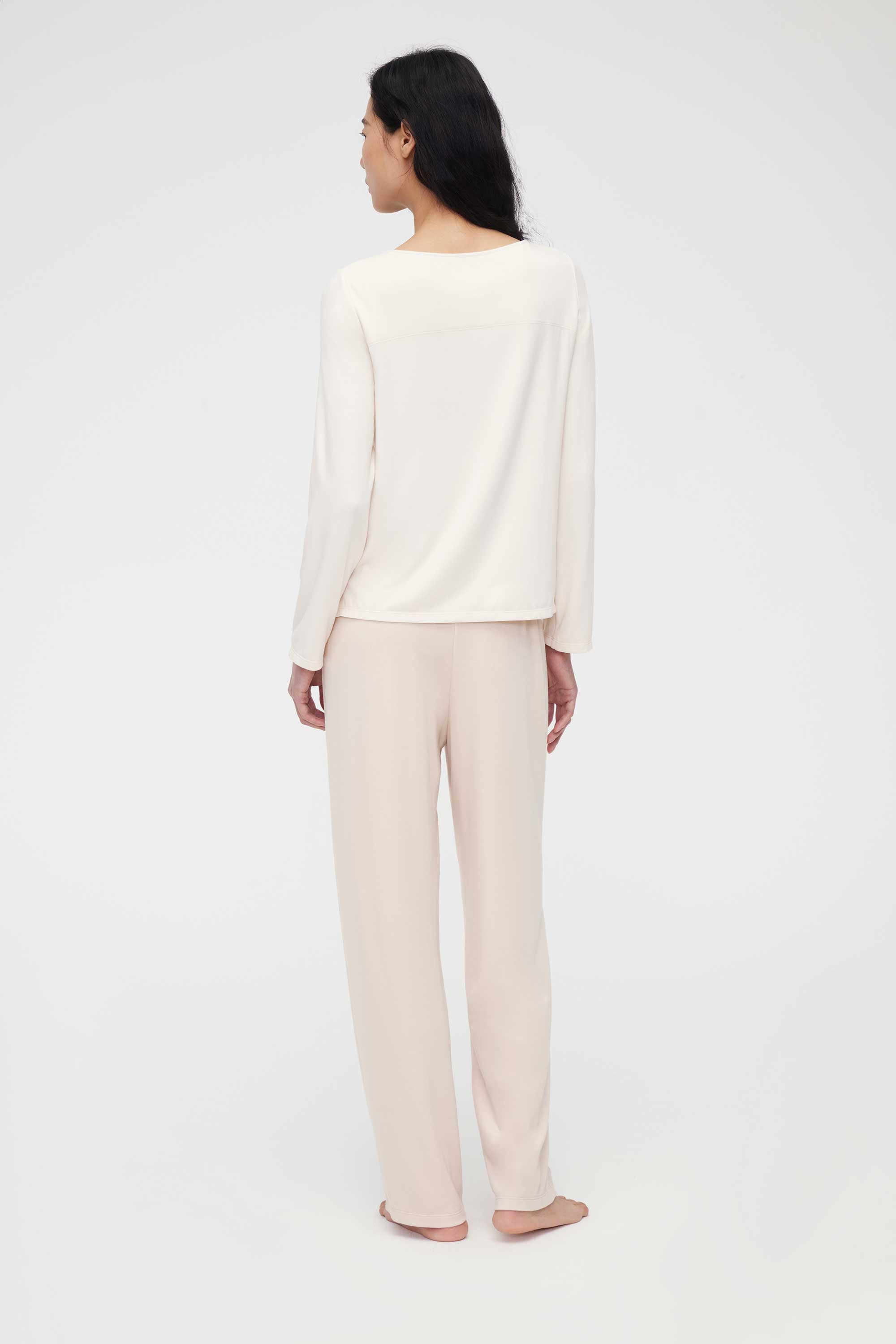back of woman in cream pajama t-shirt and pajama pants