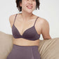 A woman wearing a purple triangle bra and purple panties and sitting on the sofa