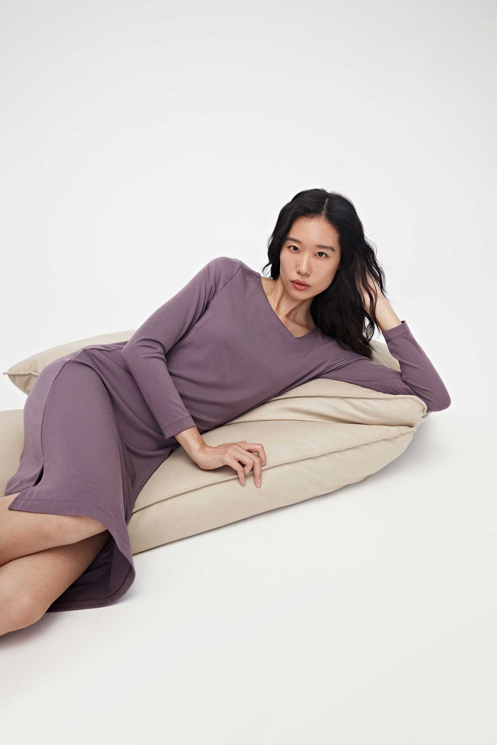 Woman wearing purple pajama dress and lying on her side on the sofa