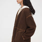Woman wearing dark brown teddy fleece jacket and facing left