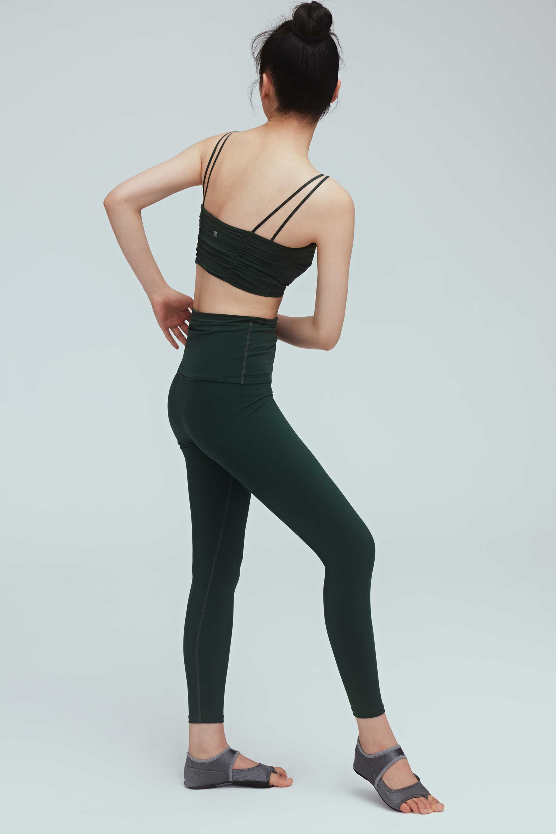back of a woman wearing a green drawstring leggings and green sports bra