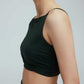 A side view of a woman wearing a crew neck dark green sports bra with pleats details.