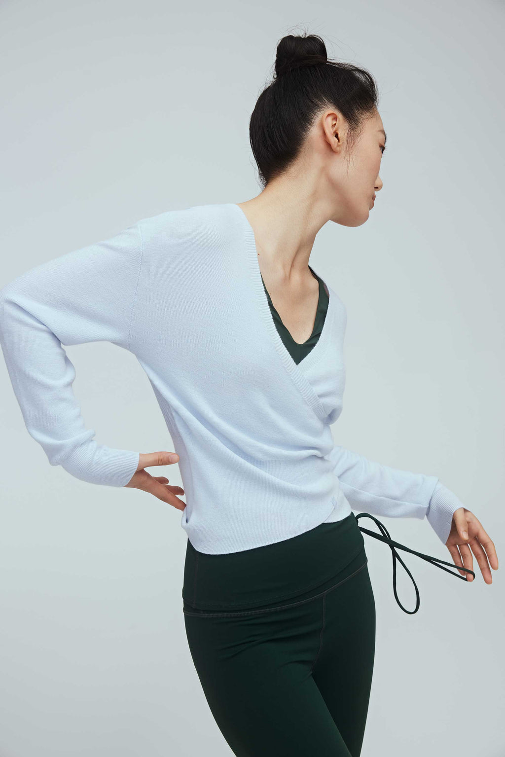 a woman wearing a blue wrap sweater and green leggings.