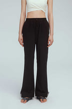 close up shot of brown joggers. the woman also wearing a white sports bra