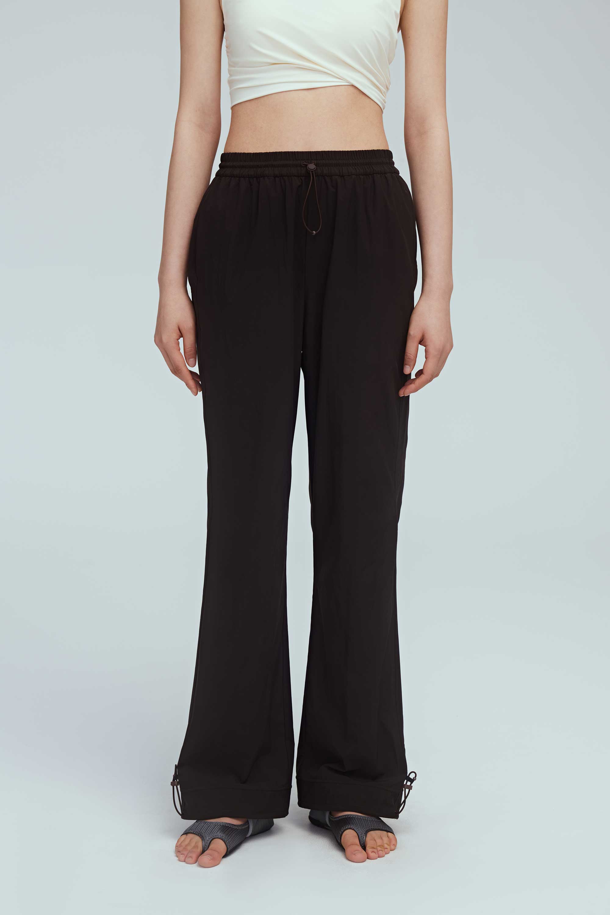 close up shot of brown joggers. the woman also wearing a white sports bra