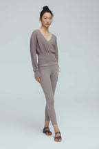 a woman wearing a taupe wrap sweater and leggings.