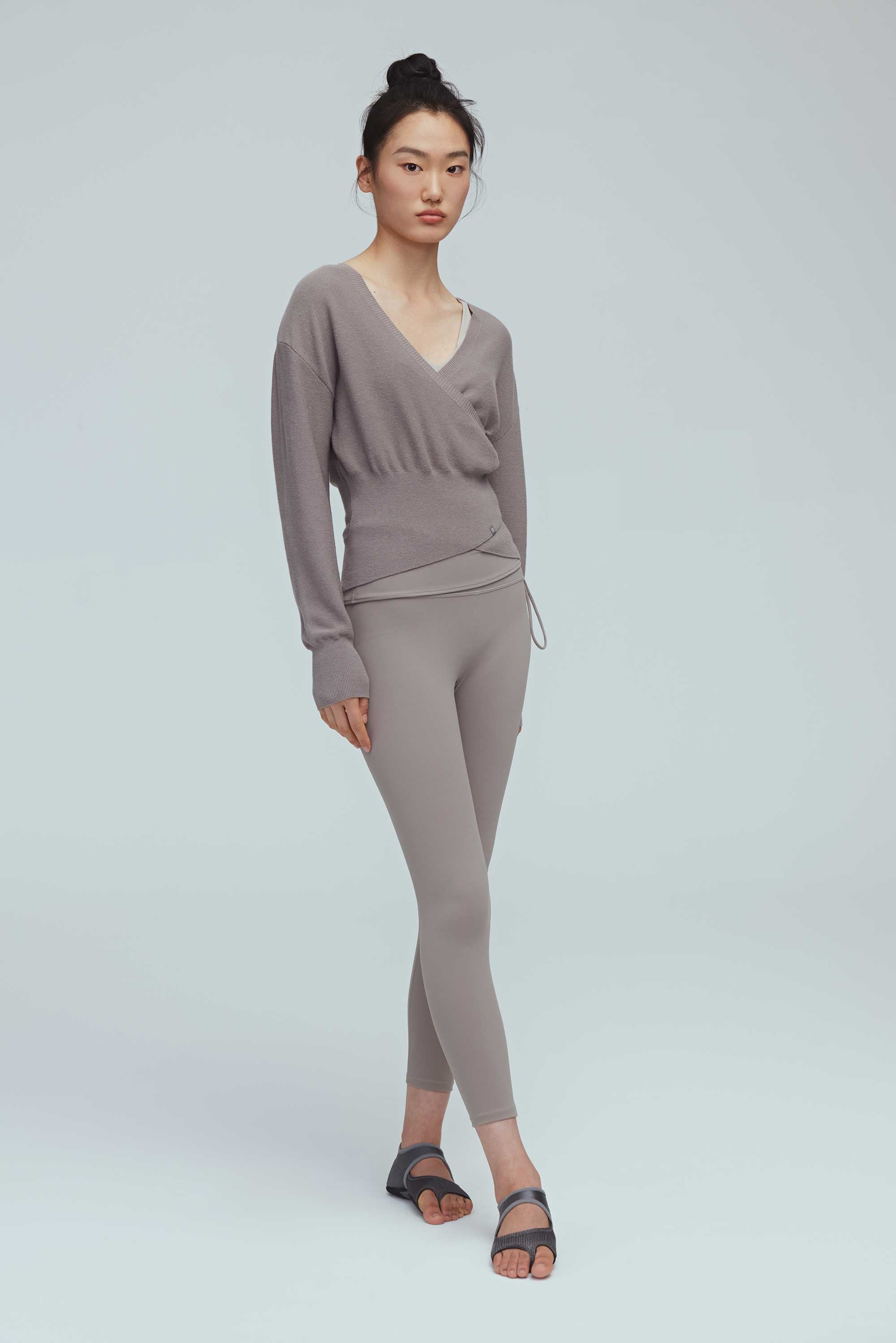 a woman wearing a taupe wrap sweater and leggings.