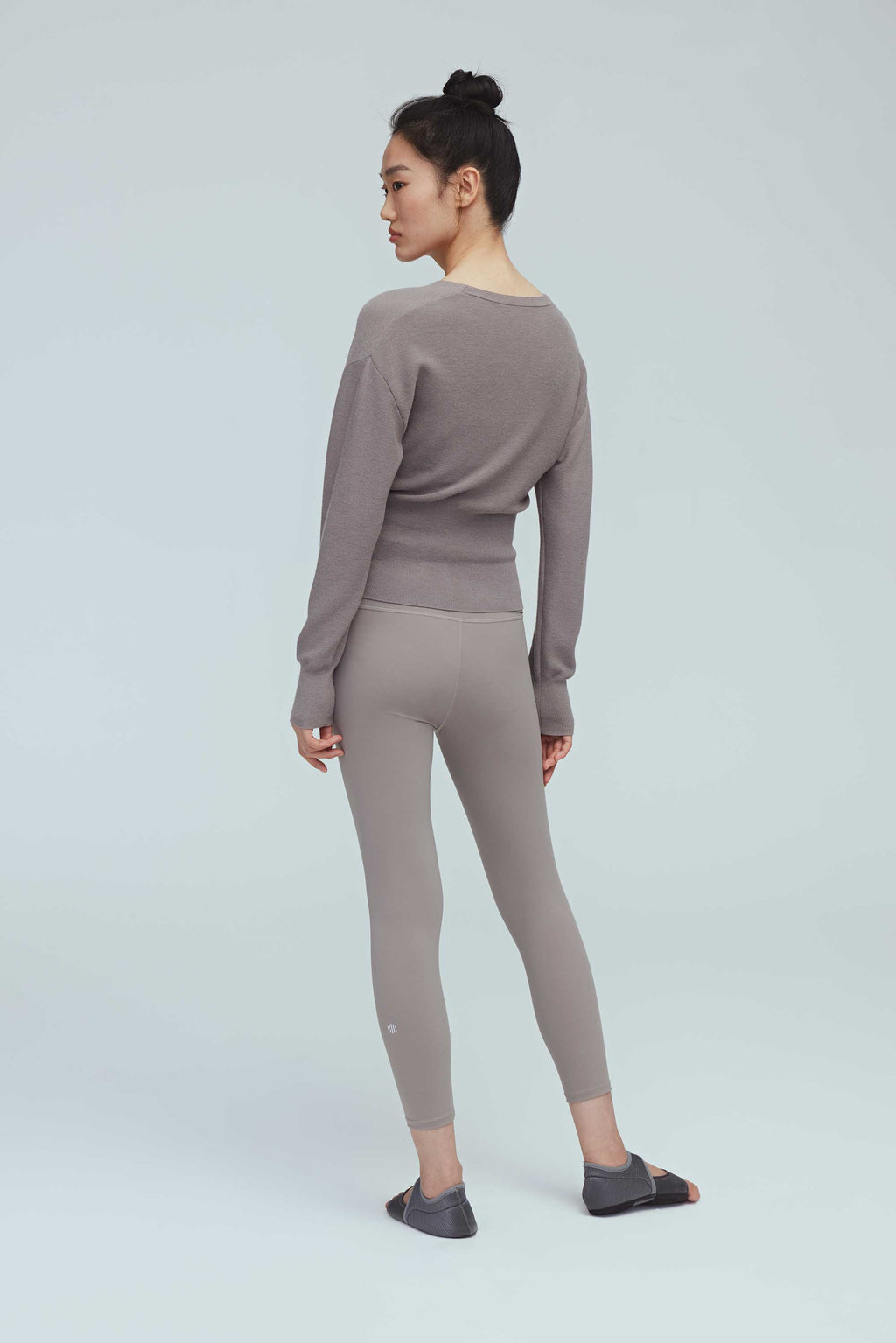 back of a woman wearing a taupe wrap sweater and leggings.