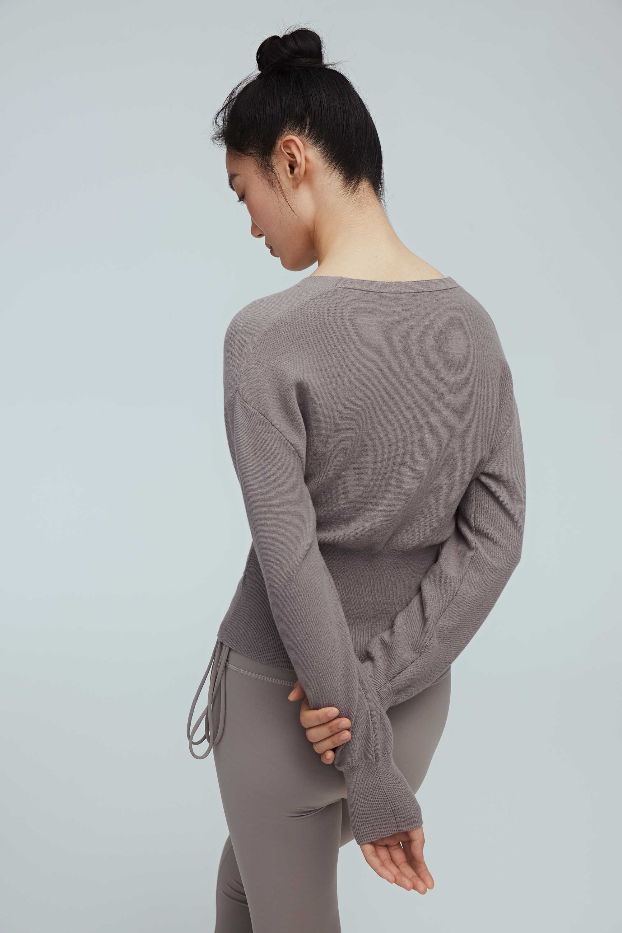 back of a woman wearing a taupe wrap sweater and leggings.