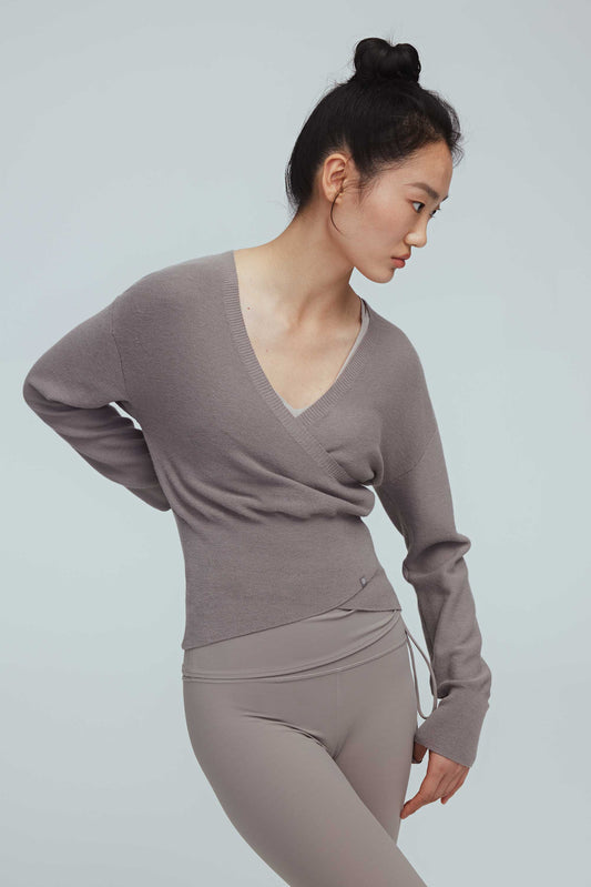 a woman wearing a taupe wrap sweater and leggings.