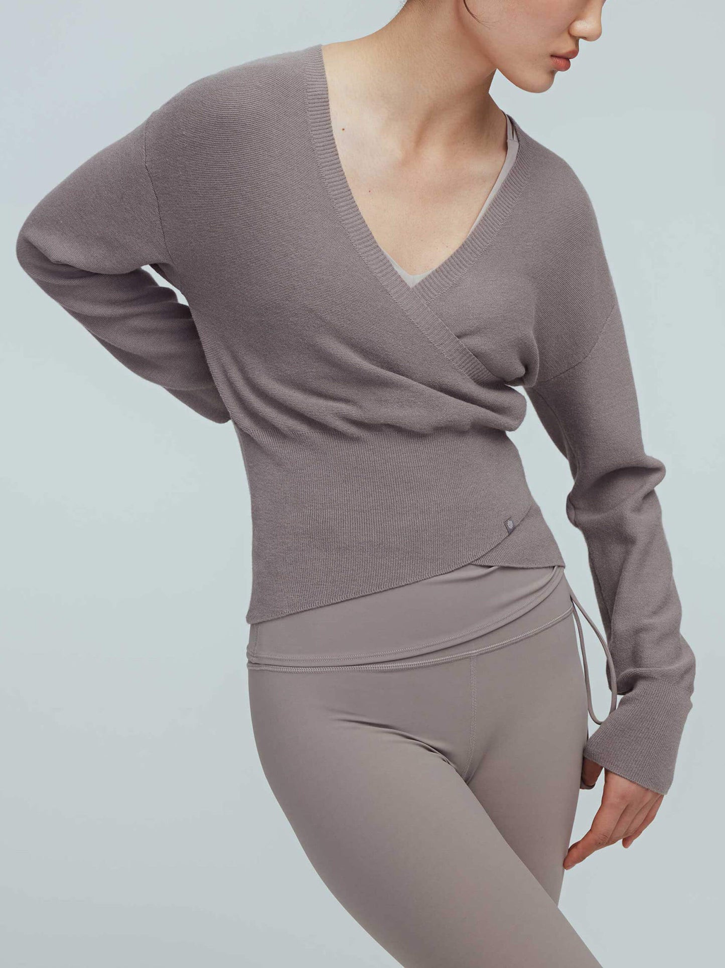 a woman wearing a taupe wrap sweater and leggings.