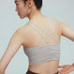 the back of a woman wearing a light grey sports bra with back crossing straps details